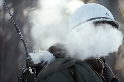 A radio operator's breath mixes with the cold Alaskan air to form a steam cloud temporarily shielding his face during Exercise BRIM FROST'87