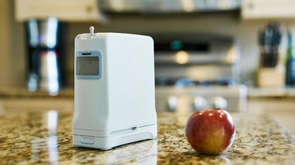 Inogen One G4 on a table with an apple next to it.