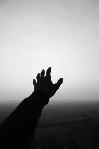 black and white photo of person reaching out with their hand.