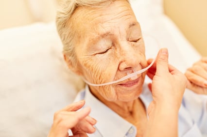 Caregiver adjusting woman's nasal cannula.