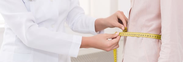 Doctor measuring a patient's waistline.