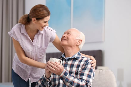 Caregiver smiling at man with a cup of coffee.