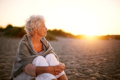 Woman sitting on a beach watching the sunset.