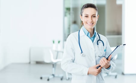 Doctor smiling while holding a clipboard.