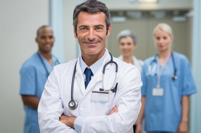 Doctor with nurses standing behind him.