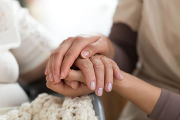 Lady holding elderly woman's hand.