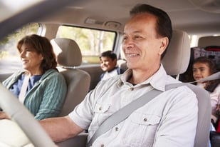 Man driving car with family.