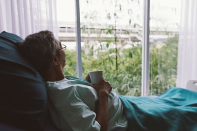 Woman laying in bed looking out the window.