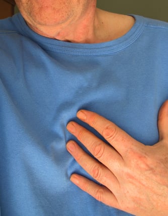 Man with blue shirt grabbing his chest.