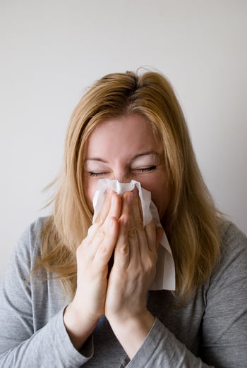 Woman blowing nose in Kleenex.