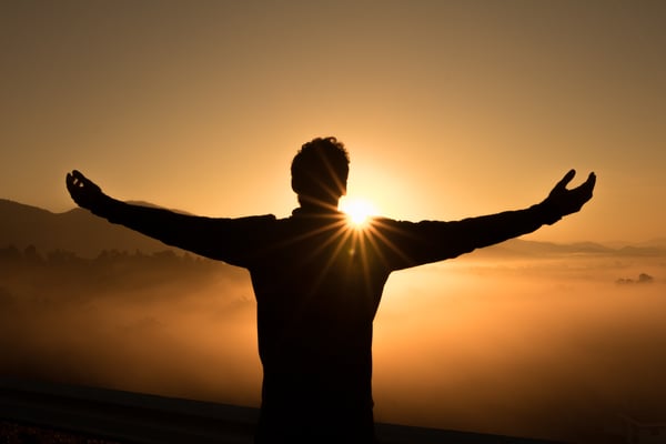 Man watching sunset with his arms out.